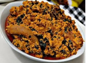 Bowl of Nigerian Egusi Soup with vegetables and assorted meats, a traditional West African melon seed soup.