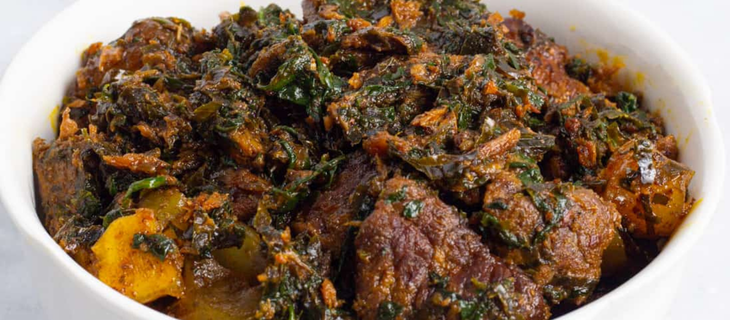 Nigerian vegetable soup with assorted meats, fresh spinach, and palm oil simmered in a rich traditional broth